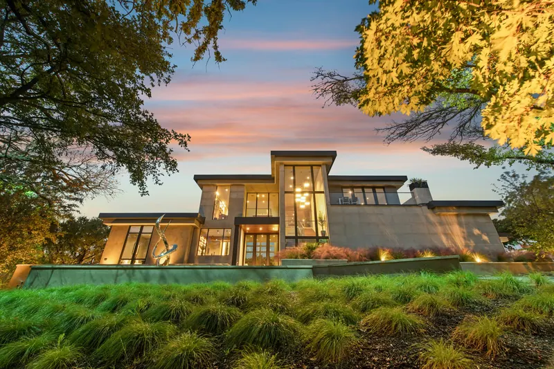 Gün batımında cephe ve bahçe aydınlatmasıyla ışıyan modern villa